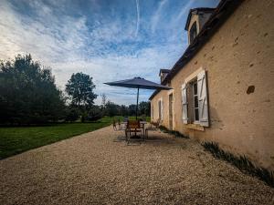 a table with an umbrella next to a building at Maison de vacances en Brenne avec piscine partagée, grand jardin et tout confort inclus - FR-1-591-329 in Bélâbre