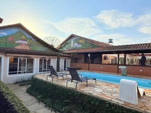a house with a swimming pool and two chairs at Pousada Castelo in Careaçu