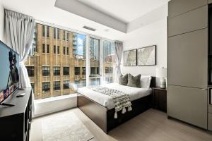 ein Schlafzimmer mit einem Bett und einem großen Fenster in der Unterkunft Modern Studio Retreat in Downtown Toronto in Toronto