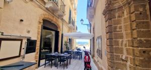 an alley with tables and chairs and an umbrella at N67 B&B Taranto Centro-3 camere indipendenti in Taranto