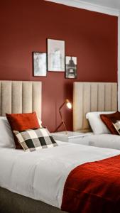a bedroom with two beds with red walls at Lovely Flat by Emirates - 5 mins to Kings Cross St Pancras in London