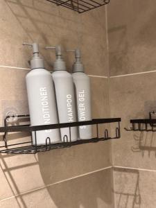 three white bottles on a shelf in a shower at Cozy one Bedroom with Views In Birmingham City Center in Birmingham +136 photos