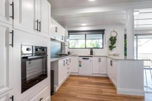 a kitchen with white cabinets and a large window at Kangaroo Point Oasis Getaway Spacious and modern in Brisbane
