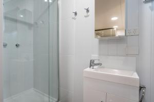 a white bathroom with a sink and a shower at Kangaroo Point Oasis Getaway Spacious and modern in Brisbane +25 photos