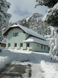 ein schneebedecktes Haus vor einem Berg in der Unterkunft Ritas Alm in Turracher Hohe