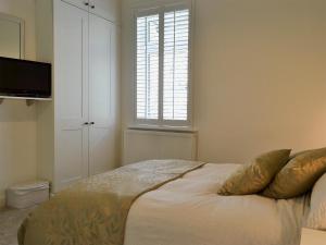 Schlafzimmer mit einem Bett mit einem Fenster und einem TV in der Unterkunft Cottage On The Green in York