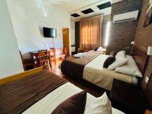 a hotel room with two beds and a television at Hotel Casa Lyon in Santiago