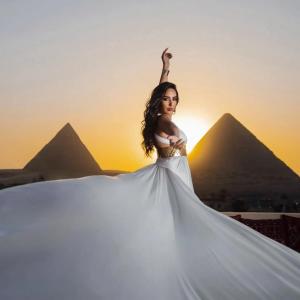 カイロにあるgrand Golden Pyramids viewのピラミッドの前でポーズをとるドレスを着た女性