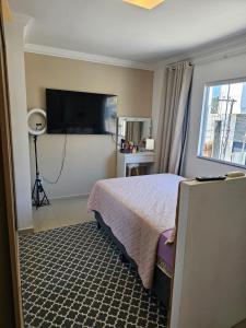 ein Hotelzimmer mit einem Bett und einem Flachbildfernseher in der Unterkunft Aproveite suas férias em família in Balneário Camboriú