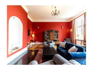 a living room with red walls and a blue couch at Groß Helle Manor House in Wrodow +32 photos