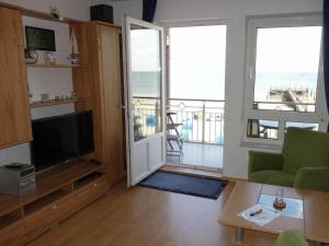 a living room with a television and a balcony at direct sea view Amrum in Wyk auf Föhr