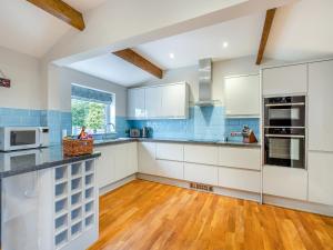 una cucina con mobili bianchi e pavimento in legno di The Cottage At Breeze Hill a Storth