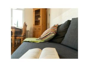 Un libro sobre un sofá con una almohada. en One-bedroom apartment, en Langeoog