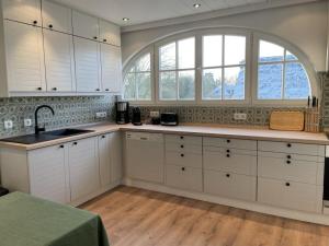 een keuken met witte kasten en een groot raam bij 1-bedroom cottage in Hornsmühlen