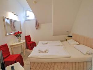 a room with a bed and two red chairs at Wellness Residence Apartment 19 in Zingst