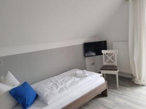 a white bed with a blue pillow and a chair at Holiday apartment with 2 bedrooms in Langenwolmsdorf