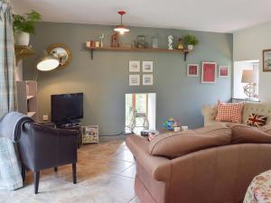 un salon avec un canapé et une télévision dans l'établissement Mill Cottage, à Llanybri