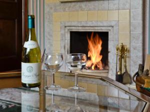 a bottle of wine and two wine glasses on a counter with a fireplace at Station House - Hw7742 in Glyn-Dyfrdwy