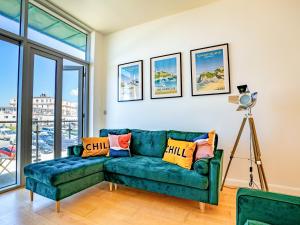 a green couch in a living room with windows at Penthouse 47 Zinc in Newquay