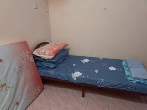 a small bed with a blue sheet and a pillow at Yanzz Homestay in Kampong Sorosob