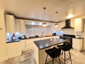 Una cocina con gabinetes blancos y una encimera negra. en Spacious 4-Bed Home with Big Backyard & Free Driveway Parking, en Barking
