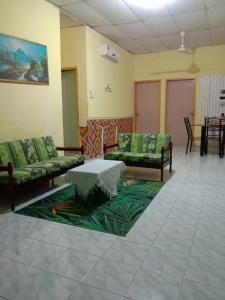 a living room with couches and a table on a rug at Yanzz Homestay in Kampong Sorosob