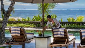 a man standing in front of a table with a drink at Villa Cemara in Sanur +13 photos