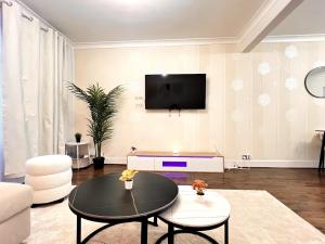 Una sala de estar con una mesa y un televisor en una pared. en Spacious 4-Bed Home with Big Backyard & Free Driveway Parking, en Barking