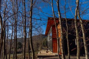 a red house with a wooden deck in the woods at The Black House in Recinto