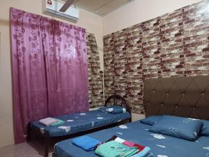 a room with two beds and a brick wall at Yanzz Homestay in Kampong Sorosob