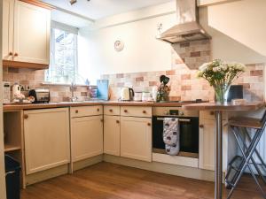 a kitchen with white cabinets and a stove top oven at Stables End in Kilnsey