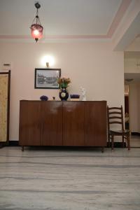 a wooden cabinet with a vase of flowers on it at Experience the grandeur of City of Joy at Anutham in Kolkata
