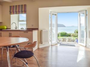 a kitchen with a table and chairs and a view of the ocean at Upper White Gates in Little Haven