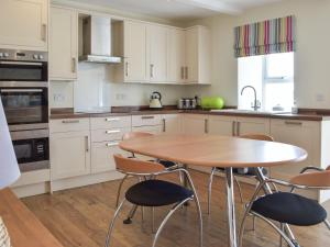 a kitchen with a wooden table and chairs at Upper White Gates in Little Haven