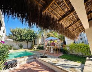 a house with a swimming pool and a straw umbrella at La Loma del Cardenal in Malinalco