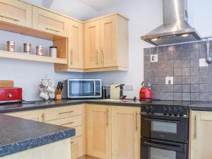 a kitchen with wooden cabinets and black appliances at Oaklea Cottage in Windermere