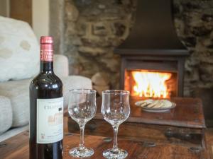 une bouteille de vin et deux verres à vin sur une table avec une cheminée dans l'établissement Lyndhurst Cottage, à Carlton