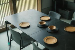 a black table with four bowls and chairs around it at OBRAs in Kasama