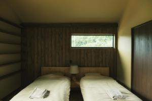 two beds in a small room with a window at OBRAs in Kasama