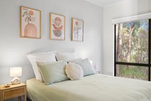 a white bedroom with a bed and a window at Otway Estate Cabins in Barongarook