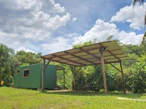 a green shed with a wooden canopy in the grass at Contenedor el Colibrí in Naranjo