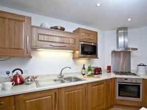 Una cocina con gabinetes de madera y un fregadero. en Bredon Court, Poseidon Penthouse, en Newquay 15 fotos más