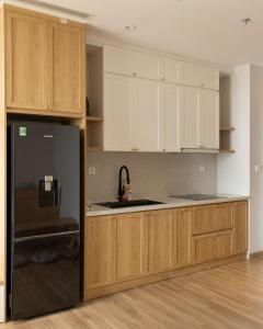 a kitchen with wooden cabinets and a black refrigerator at Sabi Room Ecopark view sông Hồng in Kim Quan