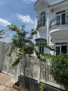 a white fence in front of a white house at Nhà nguyên căn 3 phòng ngủ in Ấp Bình Hưng