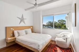 a bedroom with a bed and a chair and a window at Seaviews Little Cove Beach Noosa 2BR 200m to beach in Noosa Heads