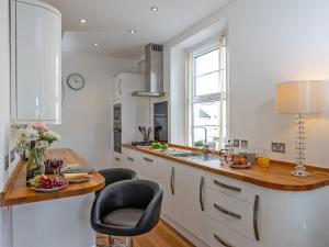 a kitchen with white cabinets and a counter with chairs at Babbacombe Bay, Torquay in Torquay