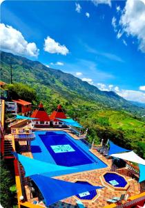 a swimming pool with blue and red umbrellas at Finca Hotel Tara in Barbosa