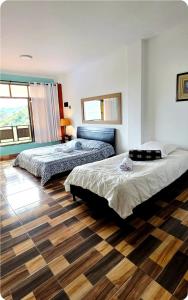 a bedroom with two beds and a wooden floor at Finca Hotel Tara in Barbosa