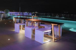 Una mesa y algunas sillas y una piscina por la noche. en Panorama Beach Pearl Condotel, en Nha Trang