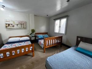 a bedroom with three beds and a window at Baguio Brentwood Villas in Baguio